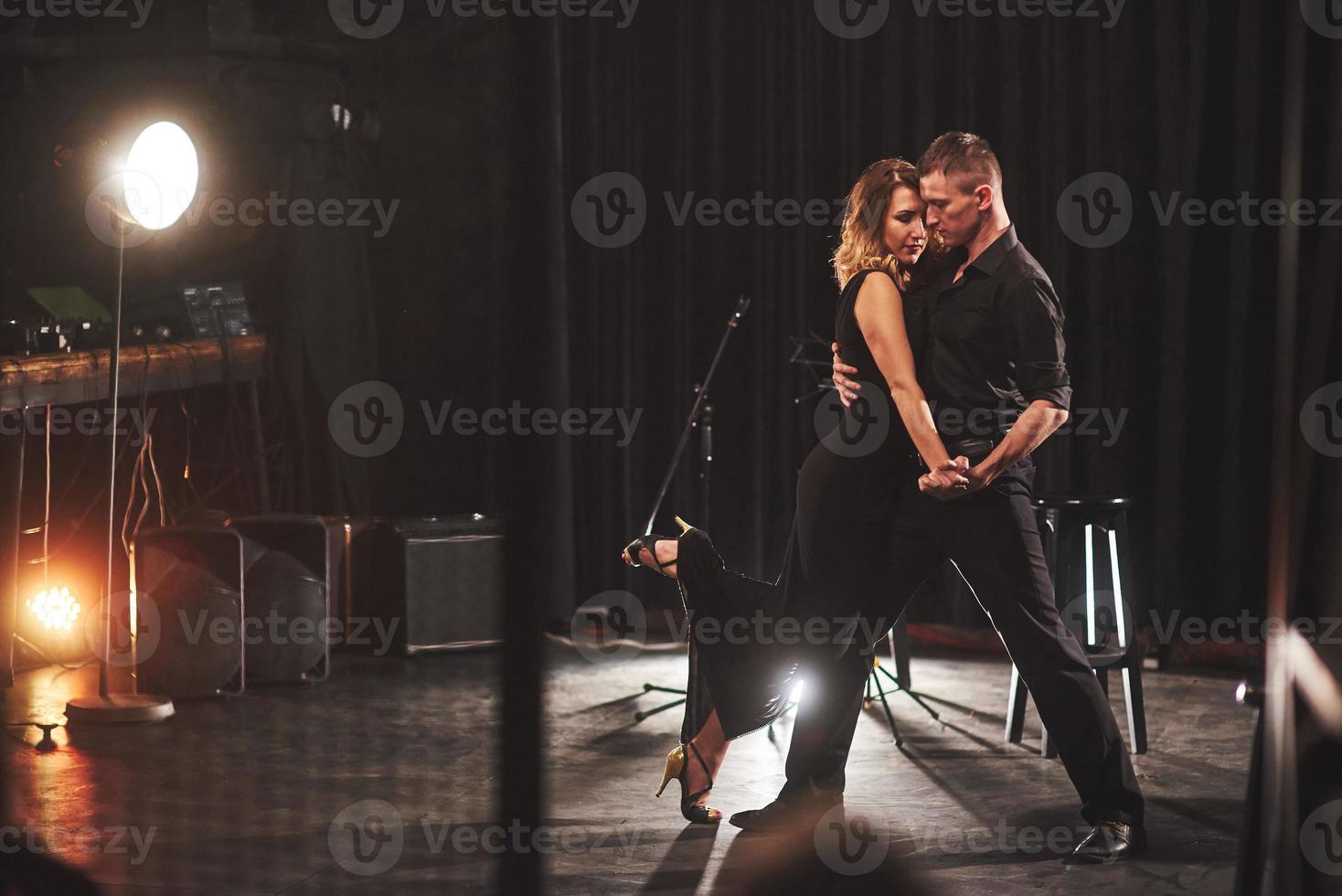 hábiles bailarines actuando en el cuarto oscuro bajo la luz foto