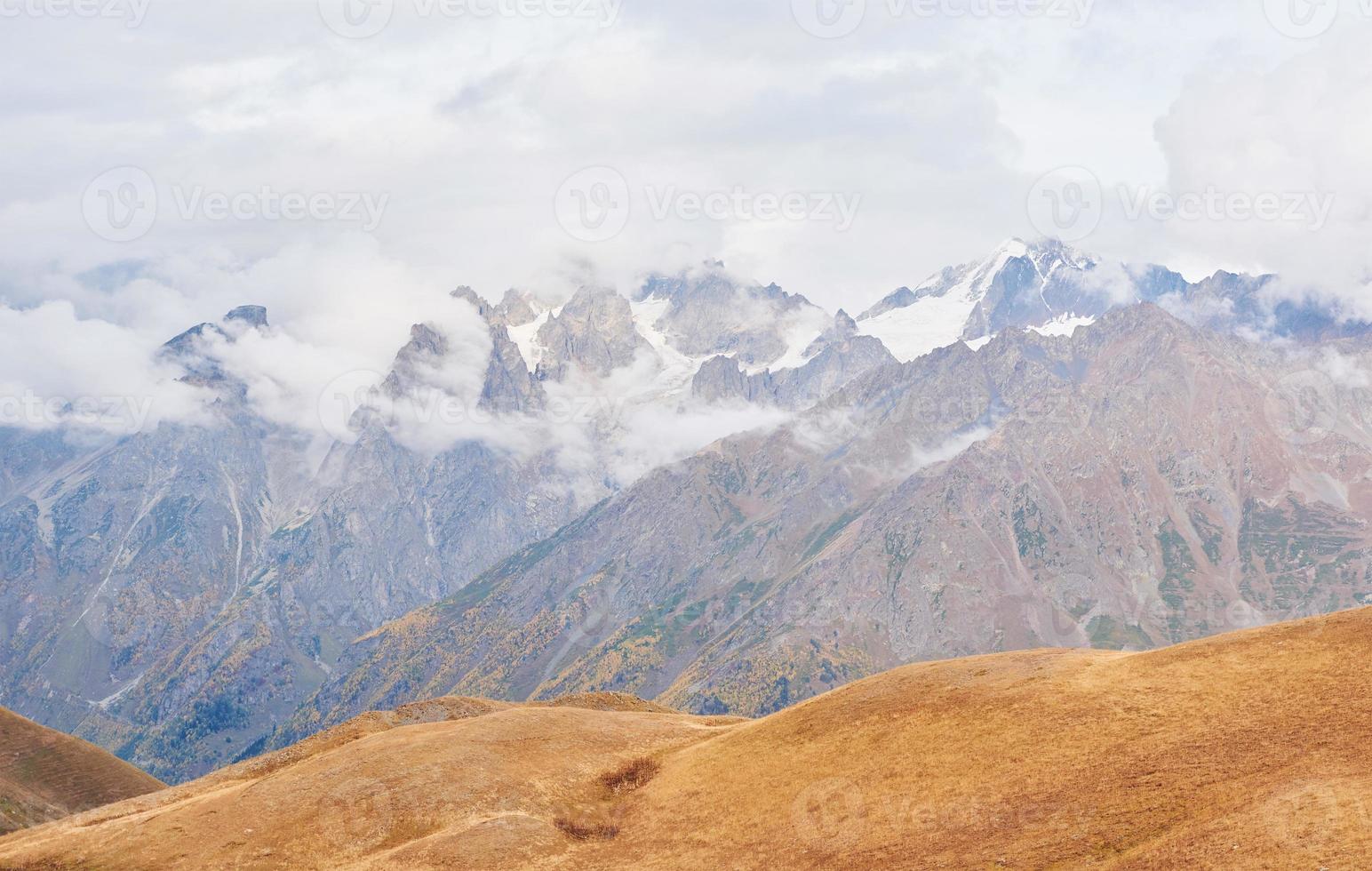 fantásticas montañas nevadas en las hermosas nubes cúmulos. dorsal caucásica principal. escriba monte ushba meyer, georgia foto