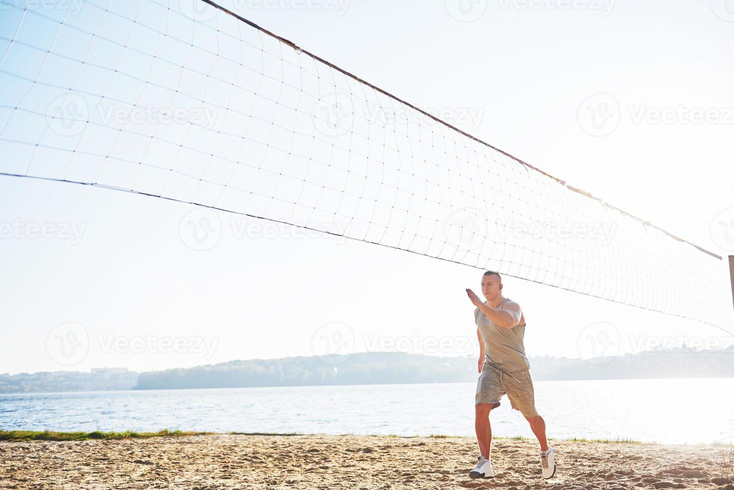 A athletic man looking at the seaside on the wild sand beach. Masculine and sporty male with naked torso is doing evening training at the sea cost. Summer work-out training outdoors photo