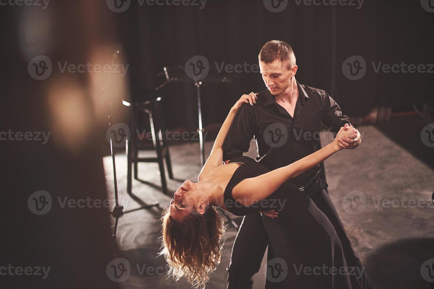 hábiles bailarines actuando en el cuarto oscuro bajo la luz foto