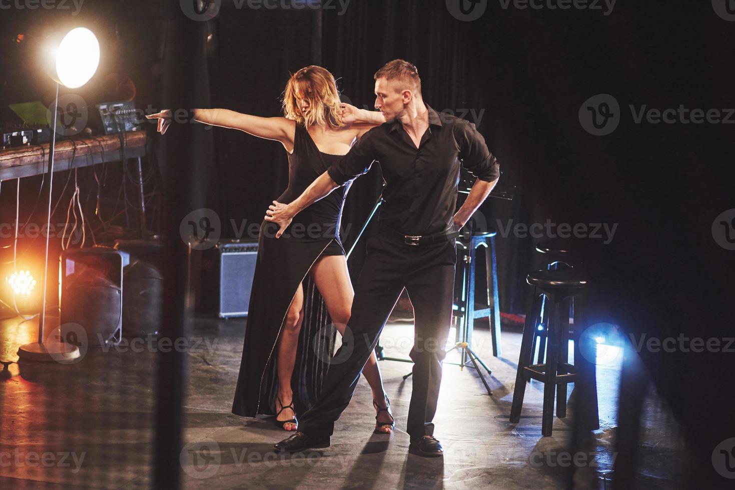 Skillful dancers performing in the dark room under the light photo