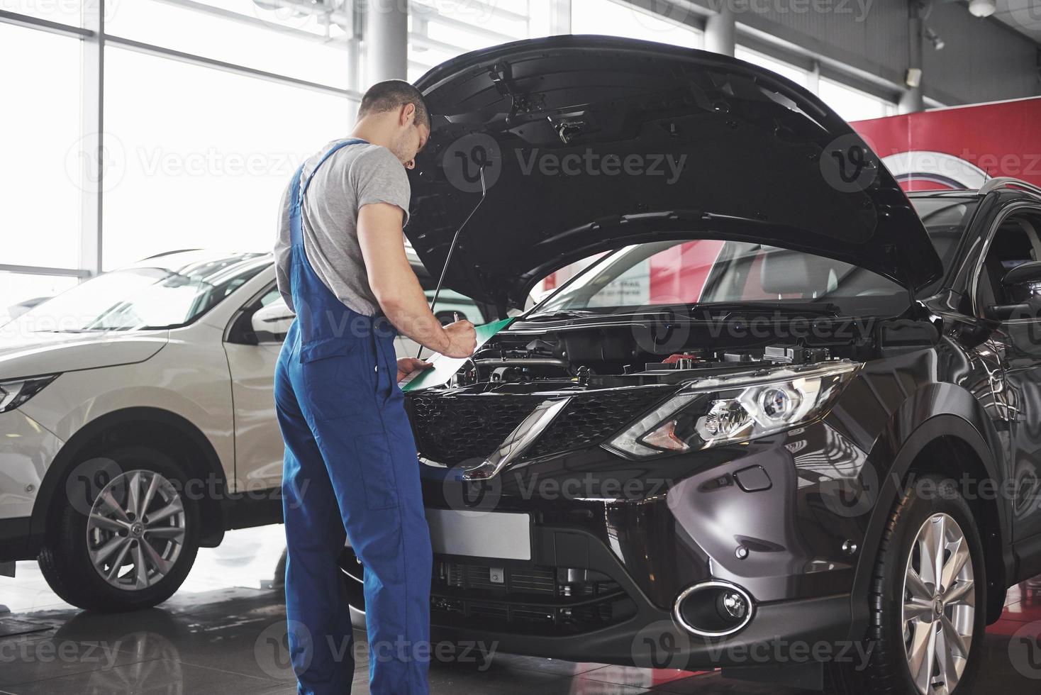 Portrait of a mechanic at work in his garage - car service, repair, maintenance and people concept photo