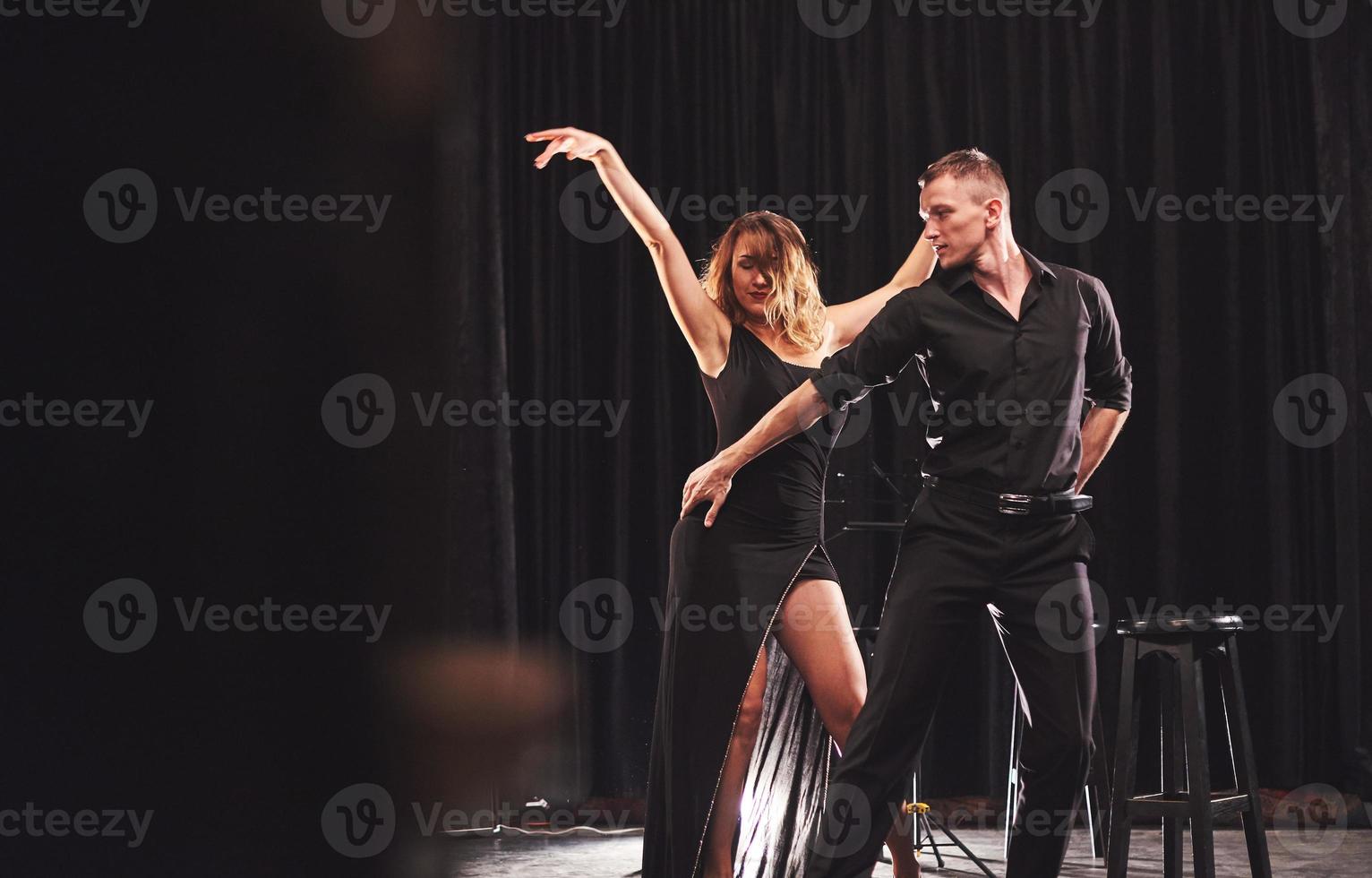 hábiles bailarines actuando en el cuarto oscuro bajo la luz foto