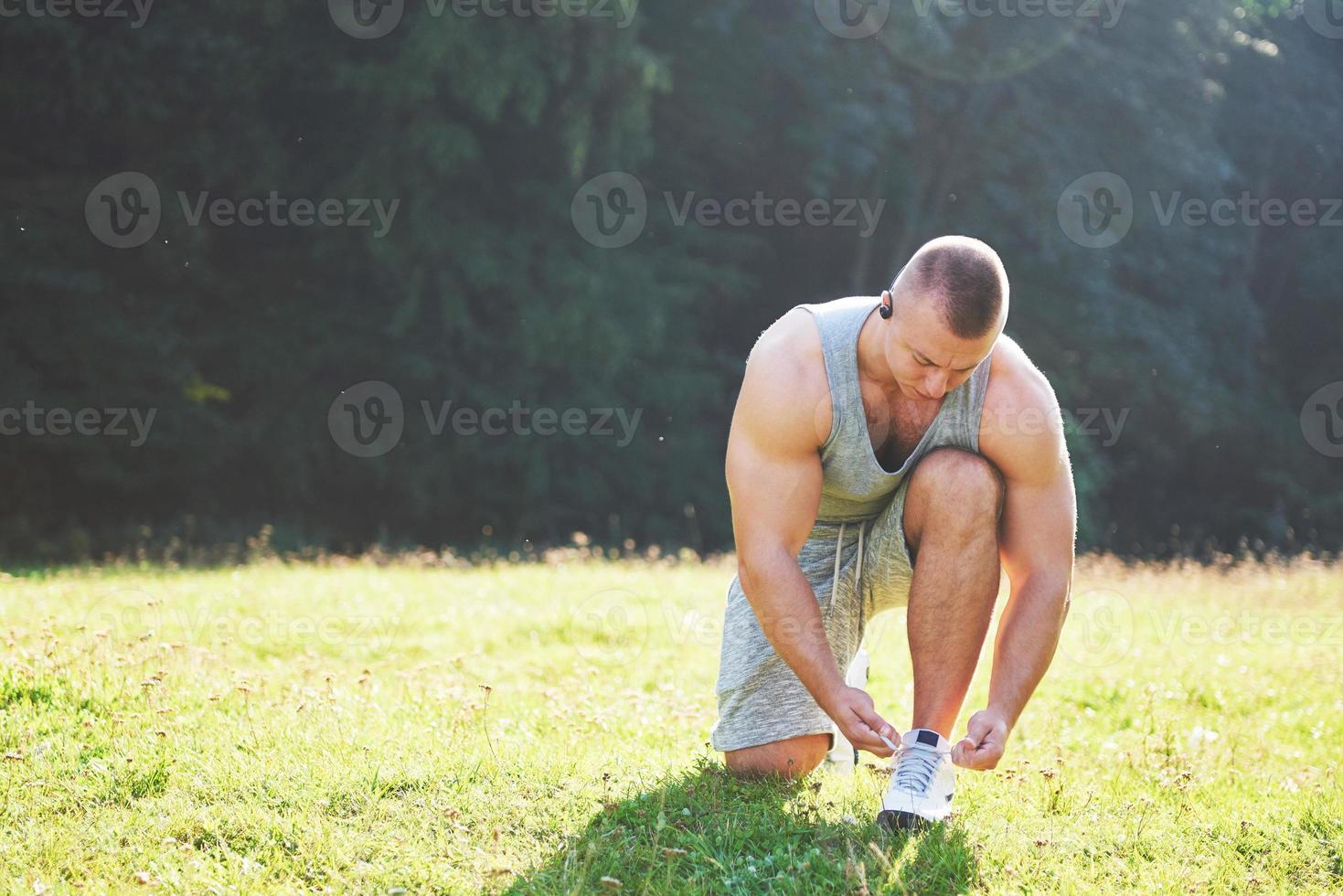 Tying sports shoe. A young sportsman getting ready for athletic and fitness training outdoors. Sport, exercise, fitness, workout. Healthy lifestyle photo
