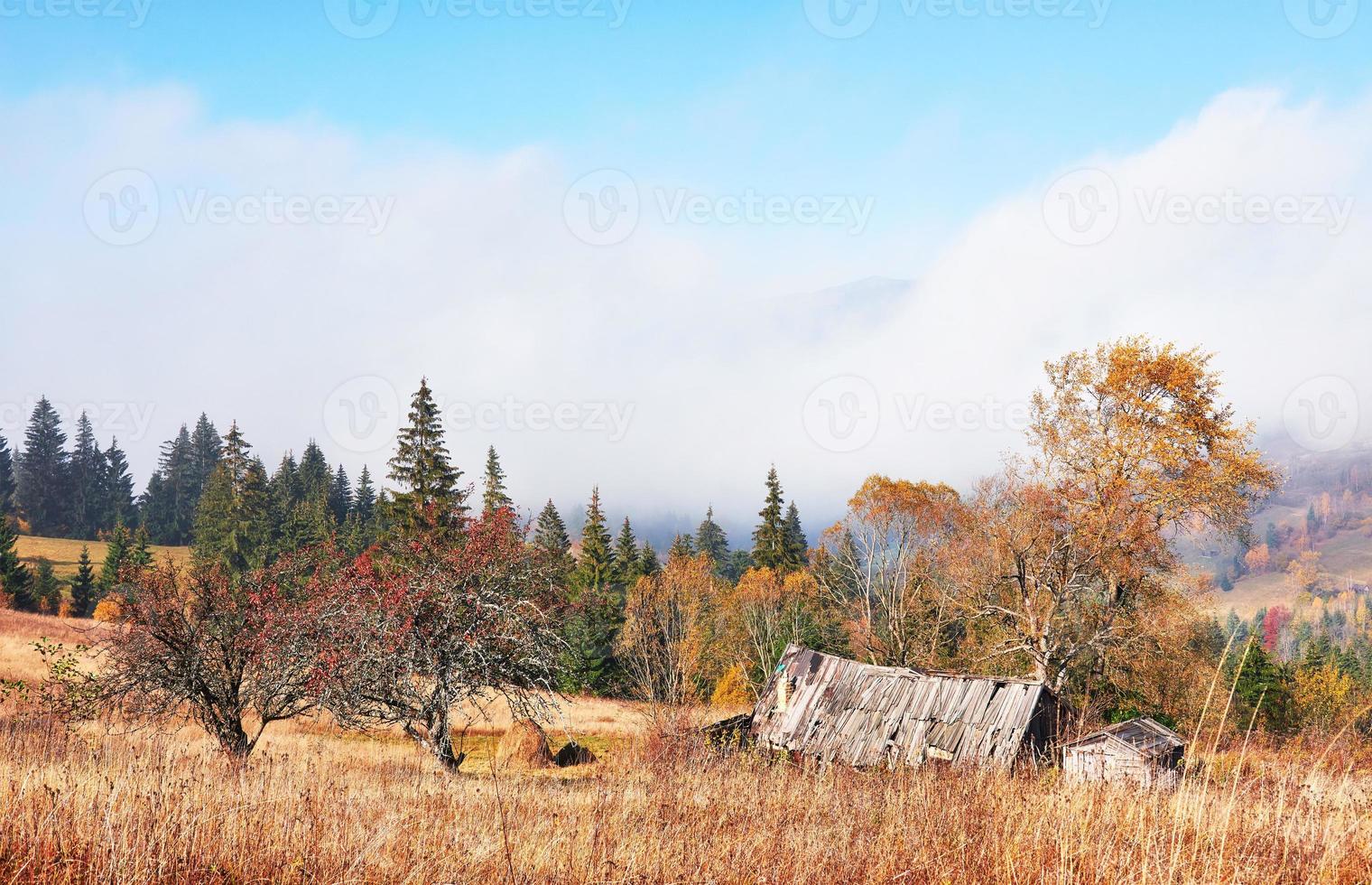 amanecer sobre el valle de niebla de alta montaña con antiguas casas de madera en una colina en un bosque de montaña foto