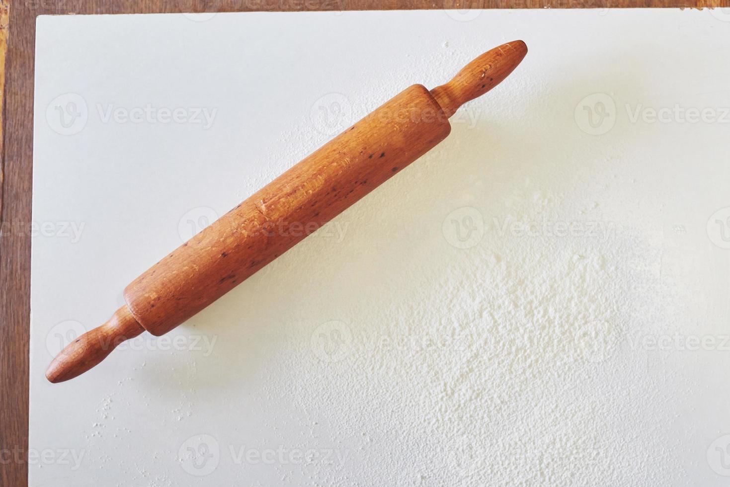 Wooden rolling pin with white wheat flour on the table. top view photo