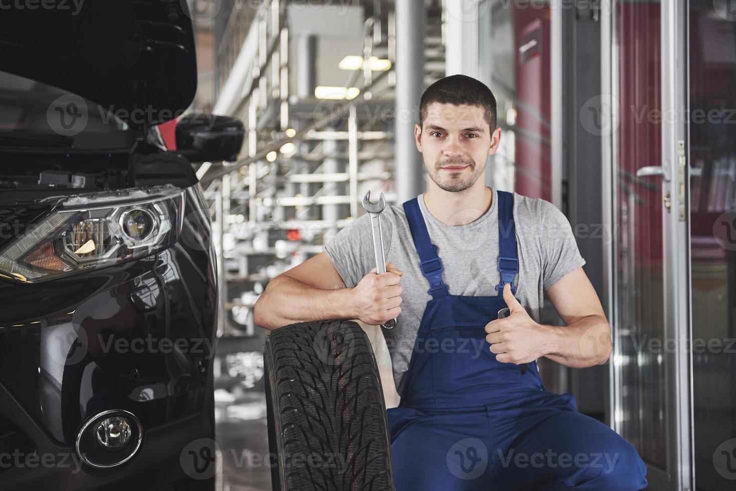 Close up of mechanic showing ok gesture with his thumb while holding a wrench photo