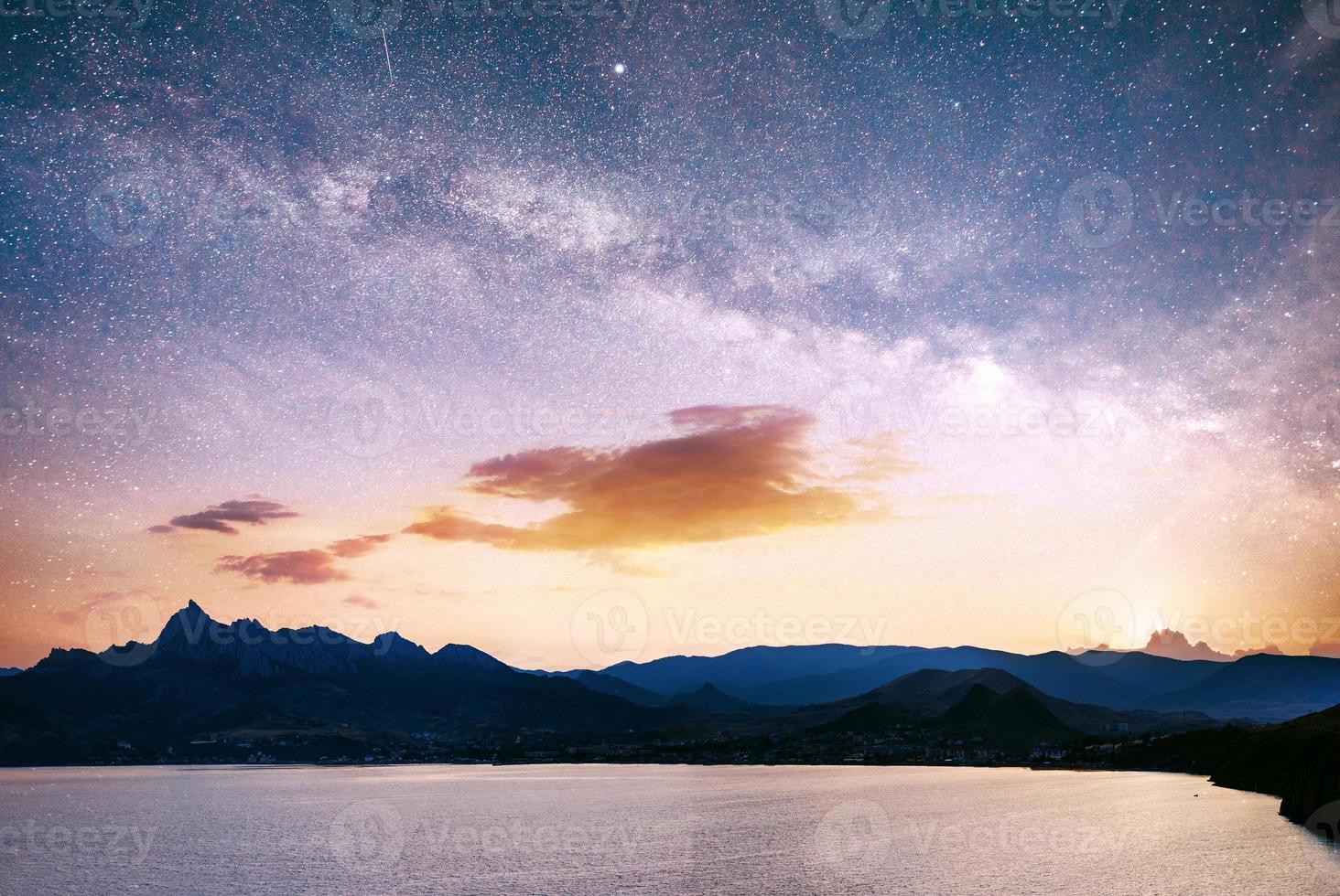 magnífico panorama de la salida del sol sobre el mar. cielo nocturno vibrante con estrellas y nebulosa y galaxia. astrofotografía de cielo profundo foto