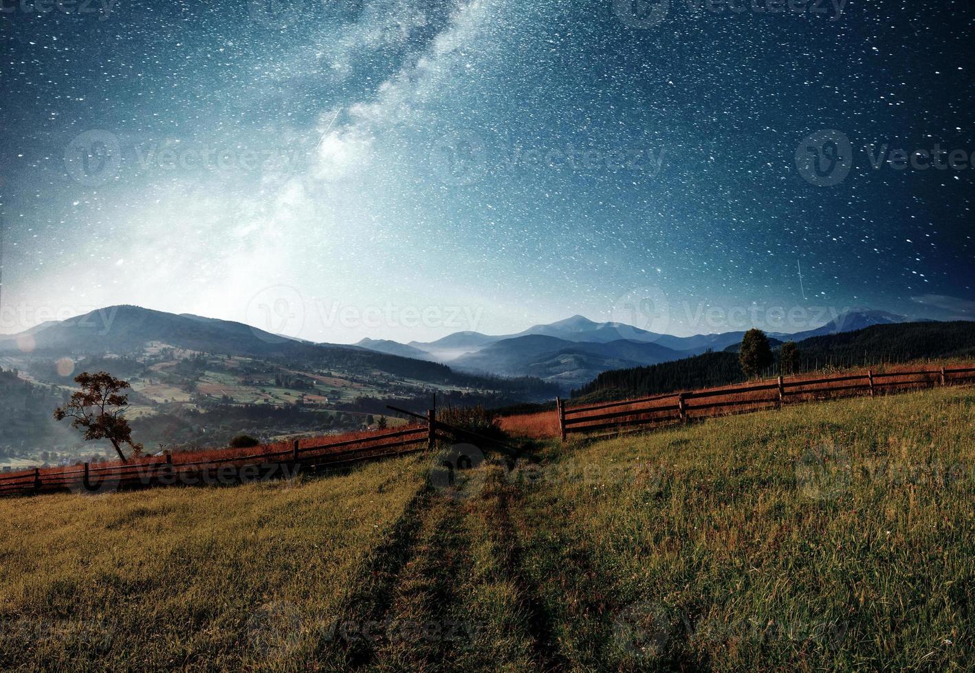 Mountain summer landscape. High grass and vibrant night sky with stars and nebula and galaxy. Deep sky astrophoto photo