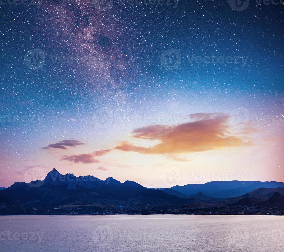 magnificent panorama of sunrise over the sea. Vibrant night sky with stars and nebula and galaxy. Deep sky astrophoto photo