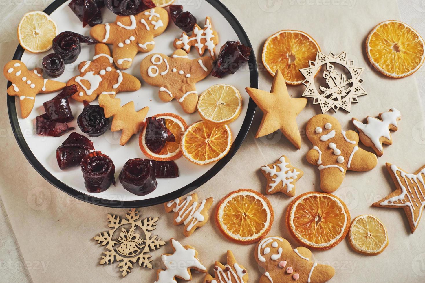 Christmas gingerbread cookies and dried orange and spices on white table. Pastel, jam in rolls on a plate photo