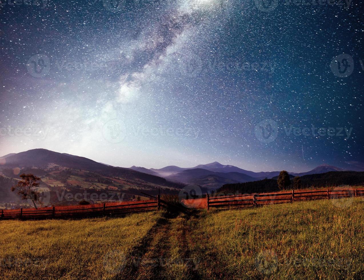 paisaje de verano de montaña. hierba alta y cielo nocturno vibrante con estrellas y nebulosa y galaxia. astrofotografía de cielo profundo foto