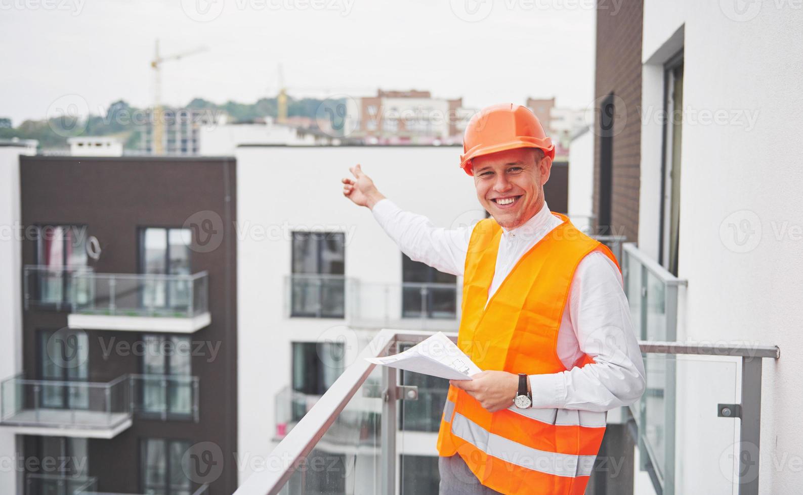 joven arquitecto con un casco protector parado en las montañas construyendo fondo al aire libre foto