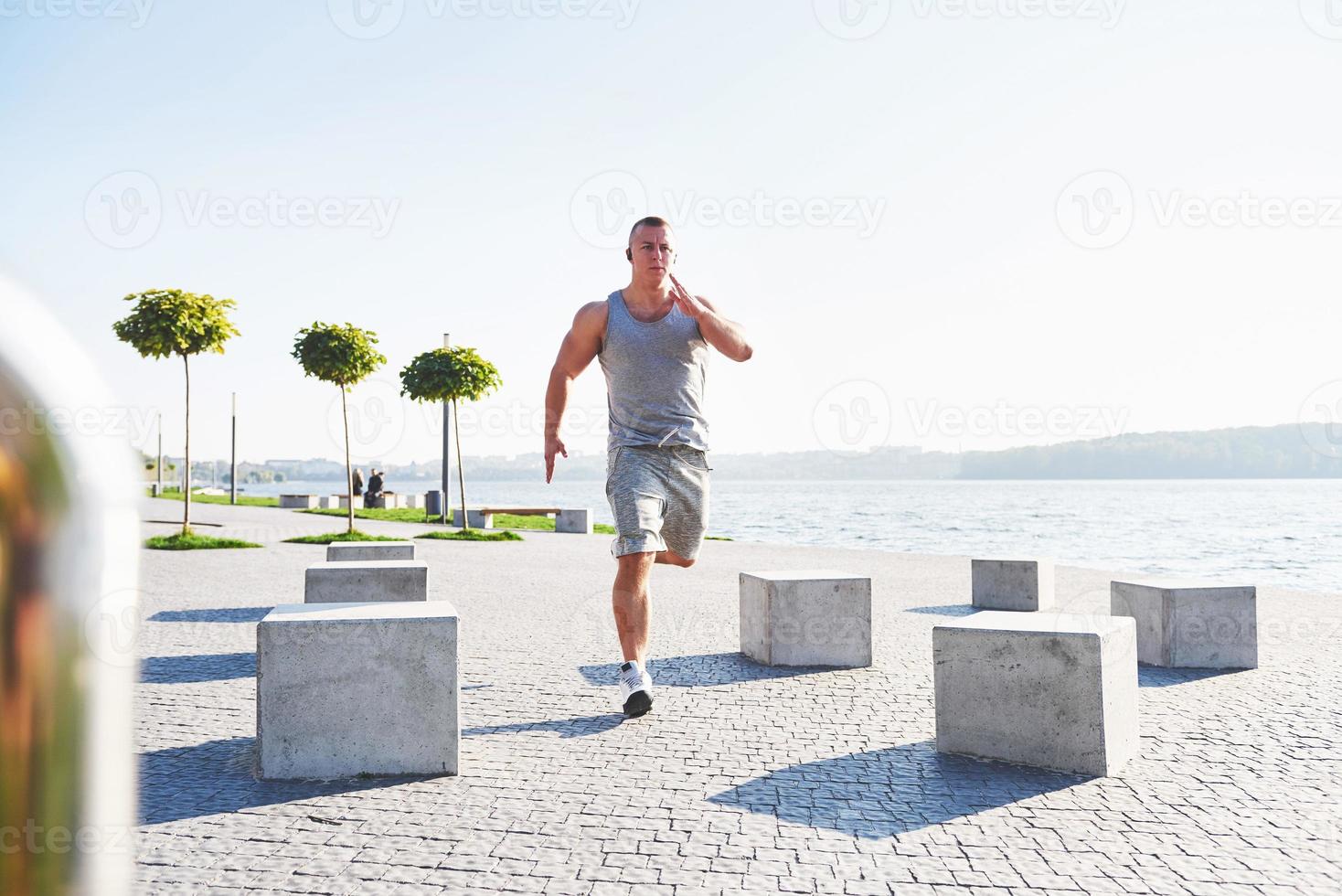 hombre corredor haciendo ejercicio de estiramiento, preparándose para el entrenamiento matutino en el parque foto