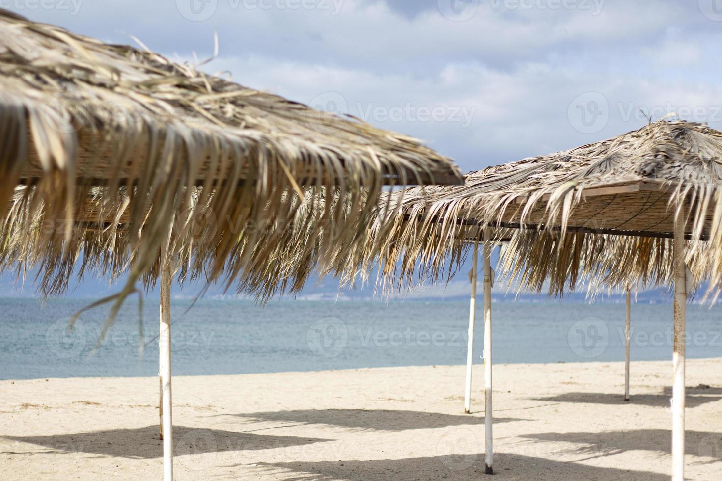 exotic beach on the beach with parasol. A lonely empty beach umbrella made of reeds. Beautiful dry branches of palm trees on the roof against the backdrop of the beach. photo