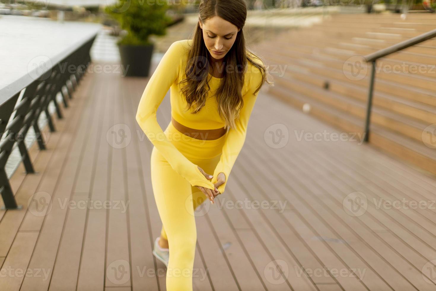 Young woman having stretching exercise on the riverside pier photo