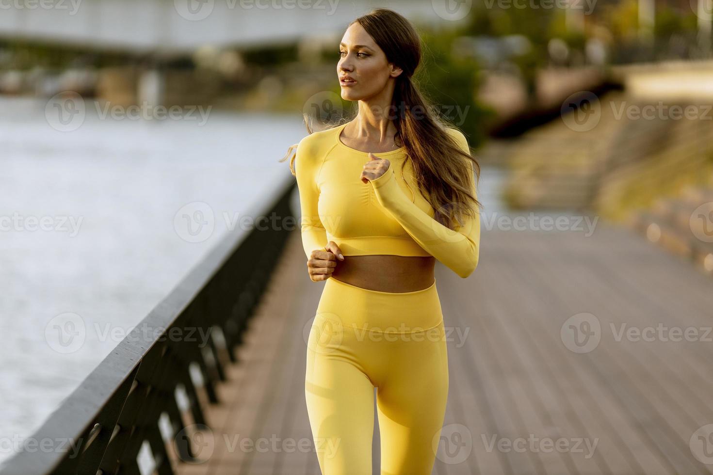 mujer joven corriendo en el muelle junto al río foto