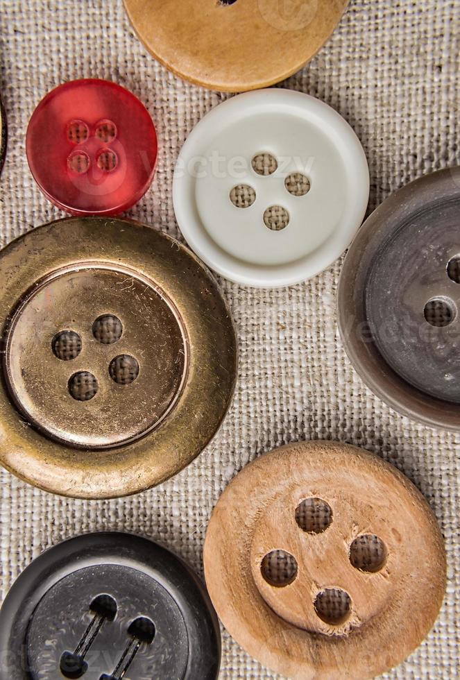 Sewing buttons of various sizes and colors on sackcloth. photo