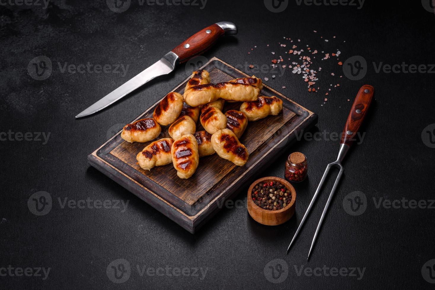Grilled sausages with spices on a dark stone background photo
