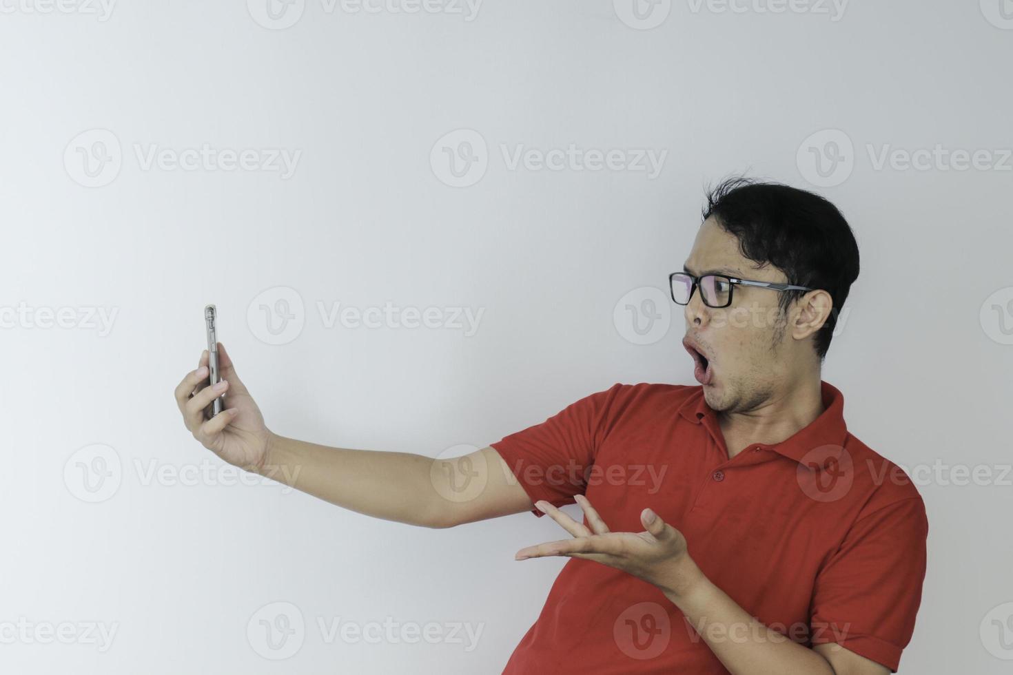 Wow face of Young Asian man shocked what he see in the smartphone on isolated grey background. photo