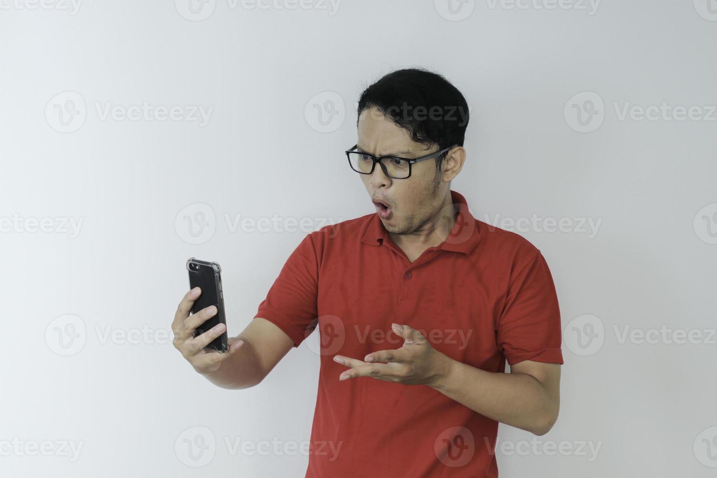 wow, la cara de un joven asiático se sorprendió por lo que vio en el teléfono inteligente con un fondo gris aislado. foto