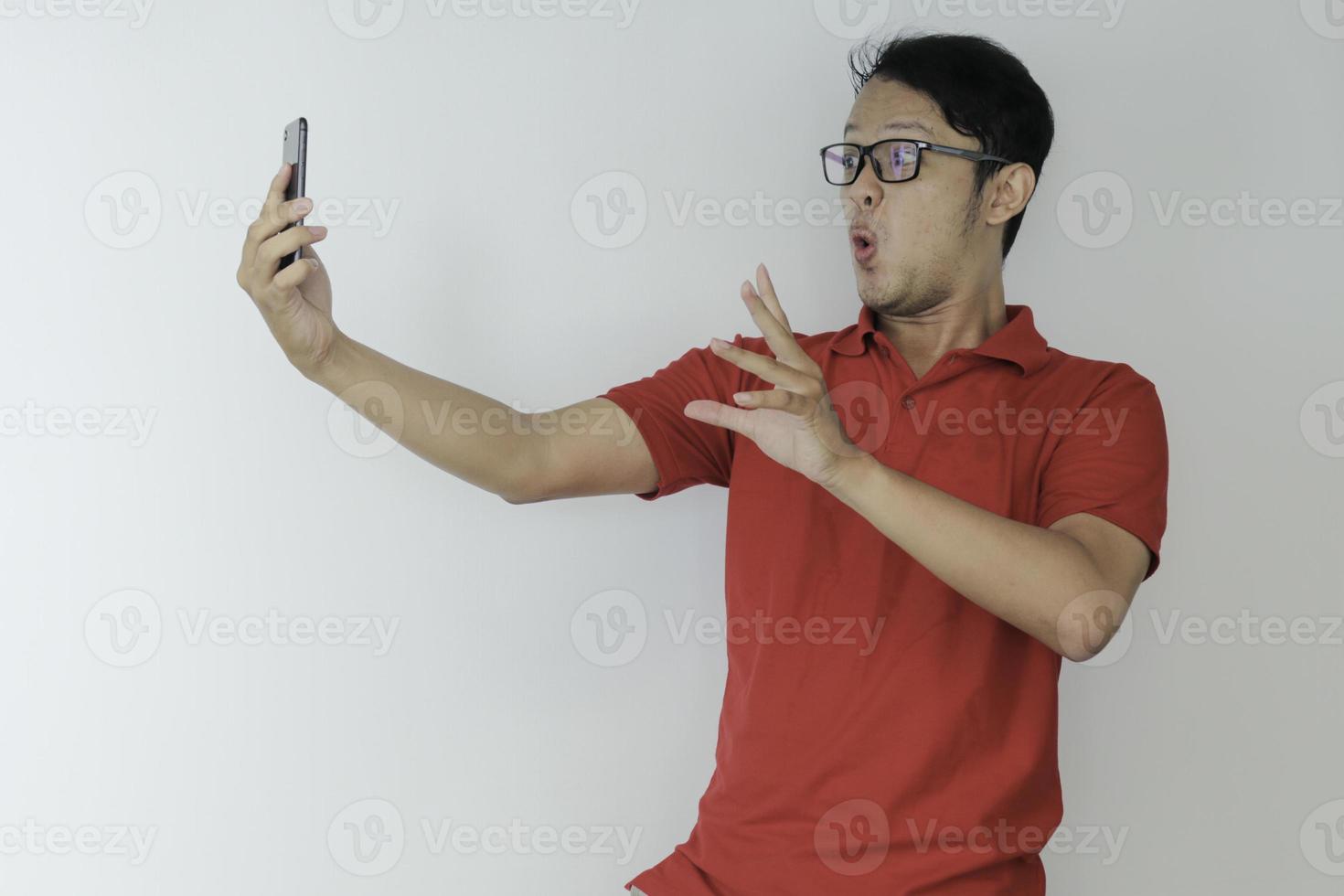 Wow face of Young Asian man shocked what he see in the smartphone on isolated grey background. photo