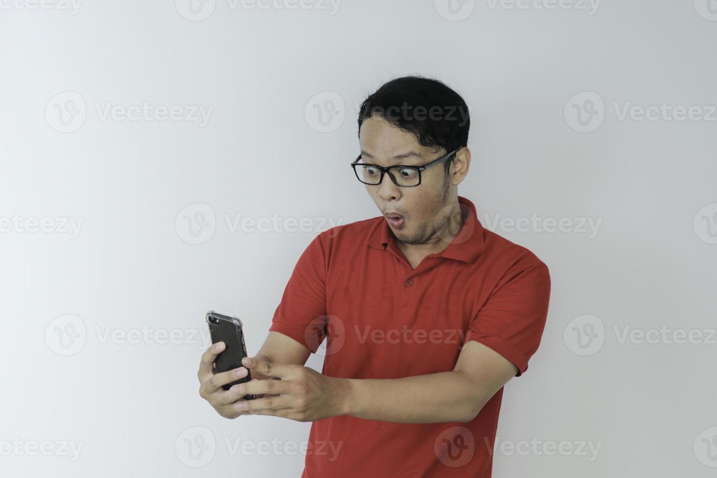 Wow face of Young Asian man shocked what he see in the smartphone on isolated grey background. photo