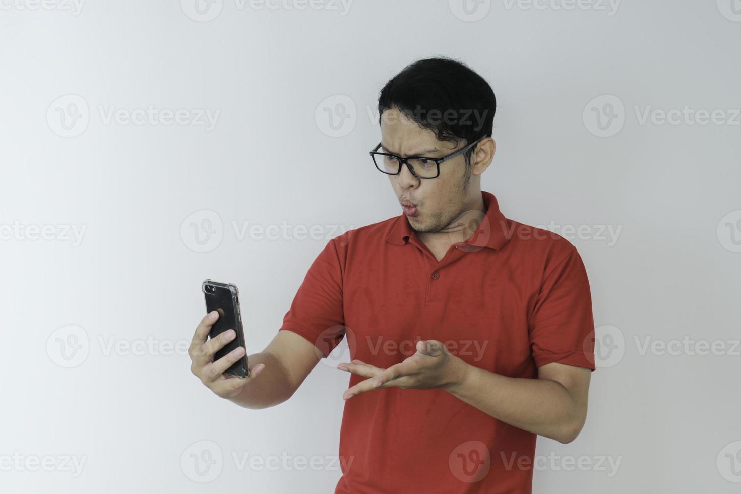 Wow face of Young Asian man shocked what he see in the smartphone on isolated grey background. photo