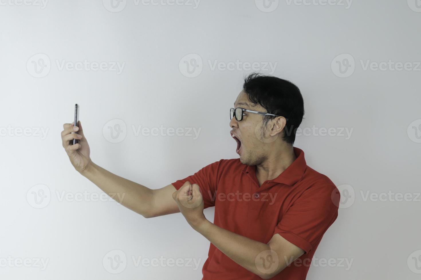 wow, la cara de un joven asiático se sorprendió por lo que vio en el teléfono inteligente con un fondo gris aislado. foto