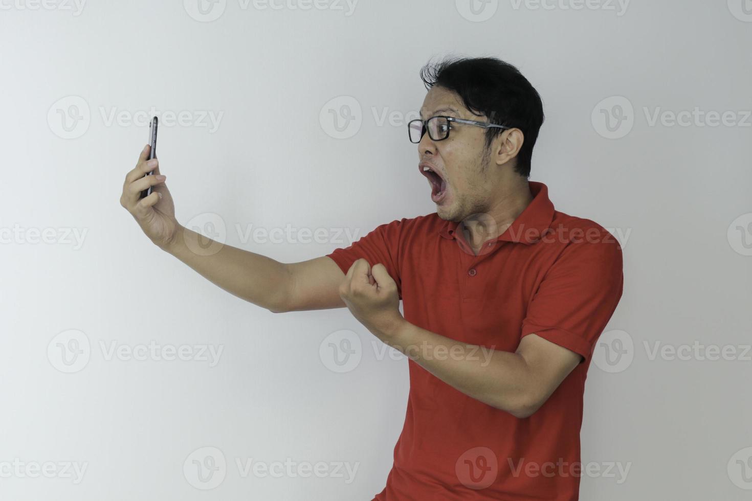 Wow face of Young Asian man shocked what he see in the smartphone on isolated grey background. photo