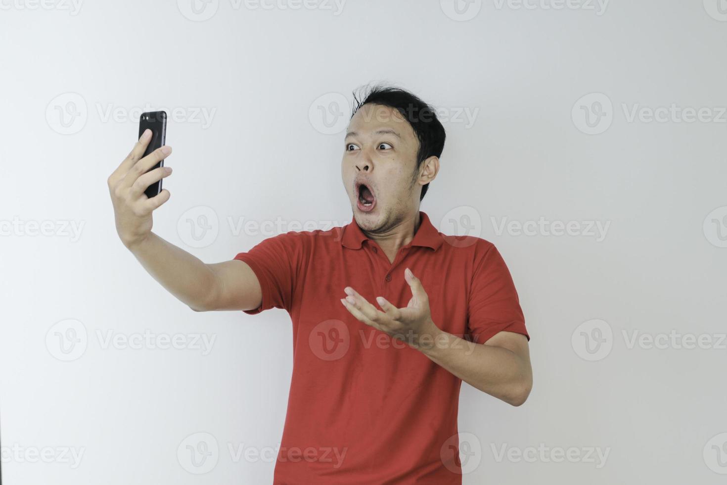 Wow face of Young Asian man shocked what he see in the smartphone on isolated grey background. photo