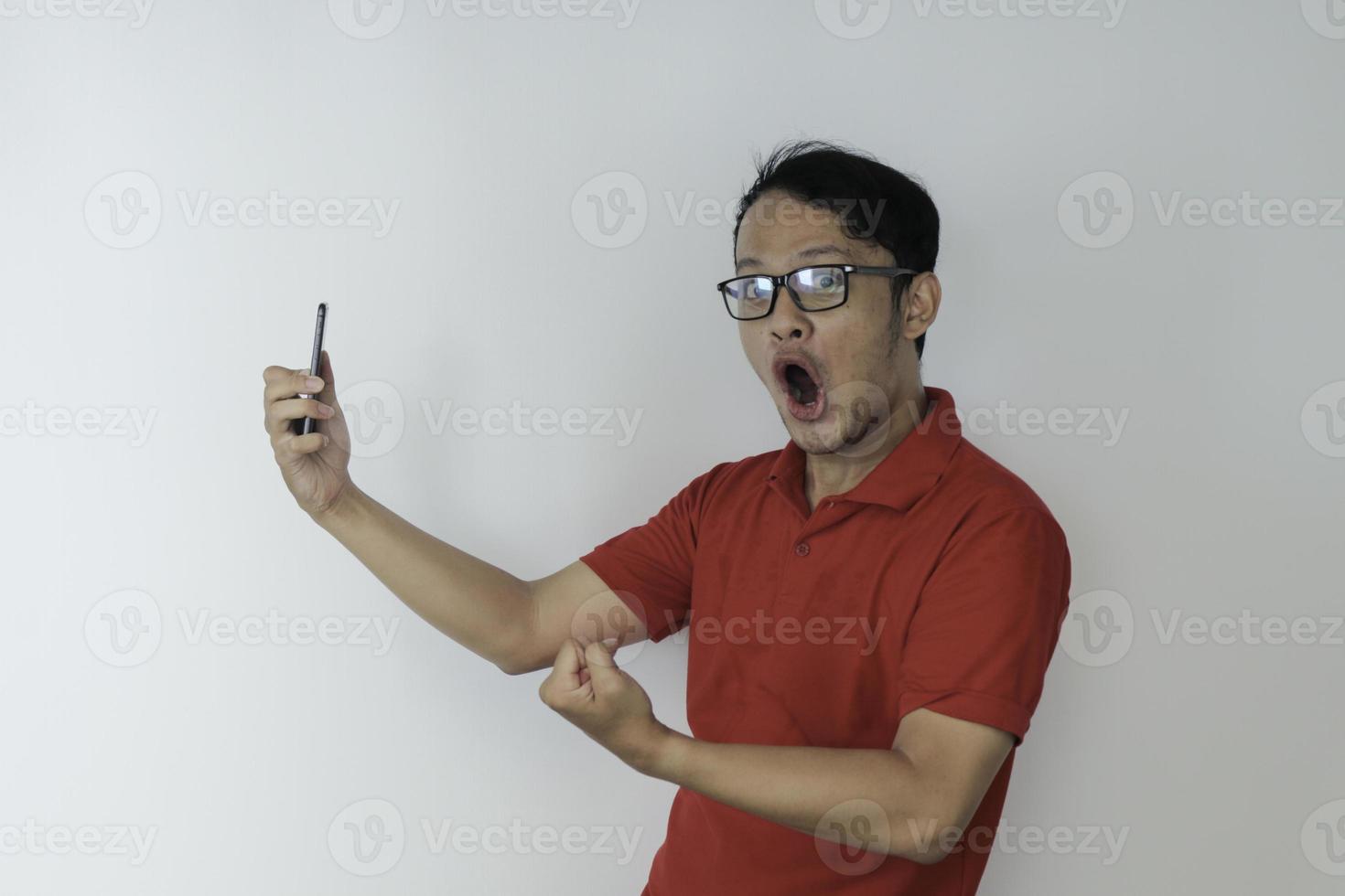 wow, la cara de un joven asiático se sorprendió por lo que vio en el teléfono inteligente con un fondo gris aislado. foto