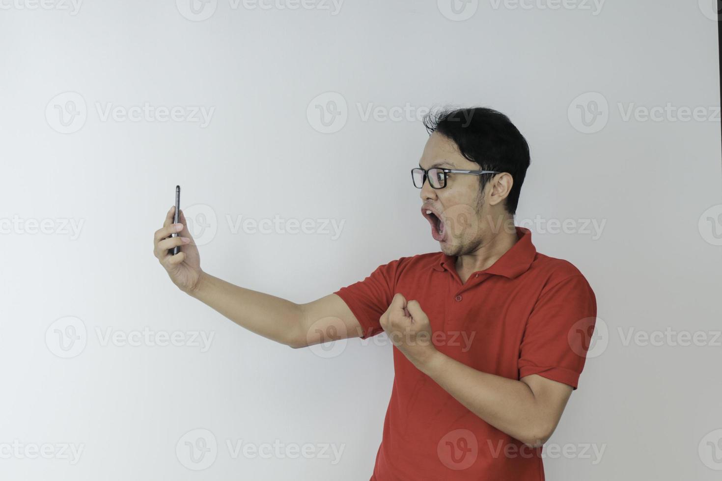 Wow face of Young Asian man shocked what he see in the smartphone on isolated grey background. photo