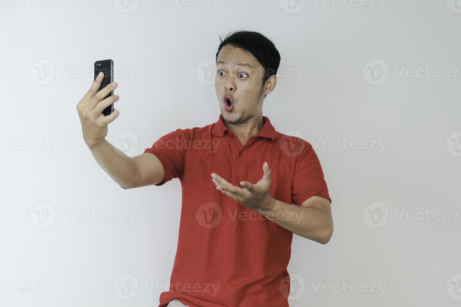 wow, la cara de un joven asiático se sorprendió por lo que vio en el teléfono inteligente con un fondo gris aislado. foto