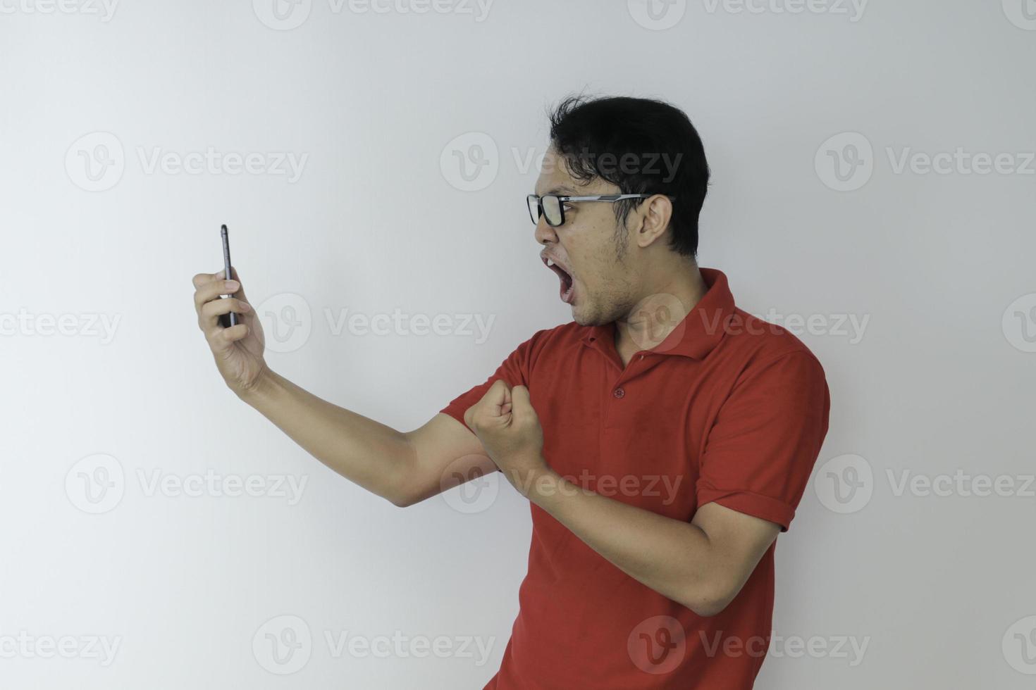 wow, la cara de un joven asiático se sorprendió por lo que vio en el teléfono inteligente con un fondo gris aislado. foto