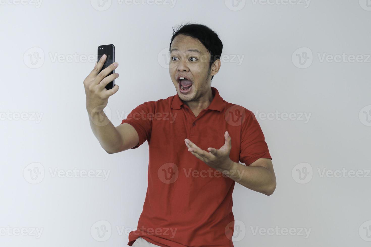 Wow face of Young Asian man shocked what he see in the smartphone on isolated grey background. photo