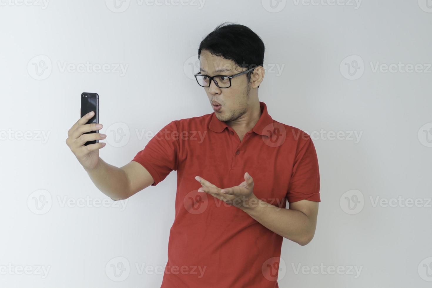 Wow face of Young Asian man shocked what he see in the smartphone on isolated grey background. photo