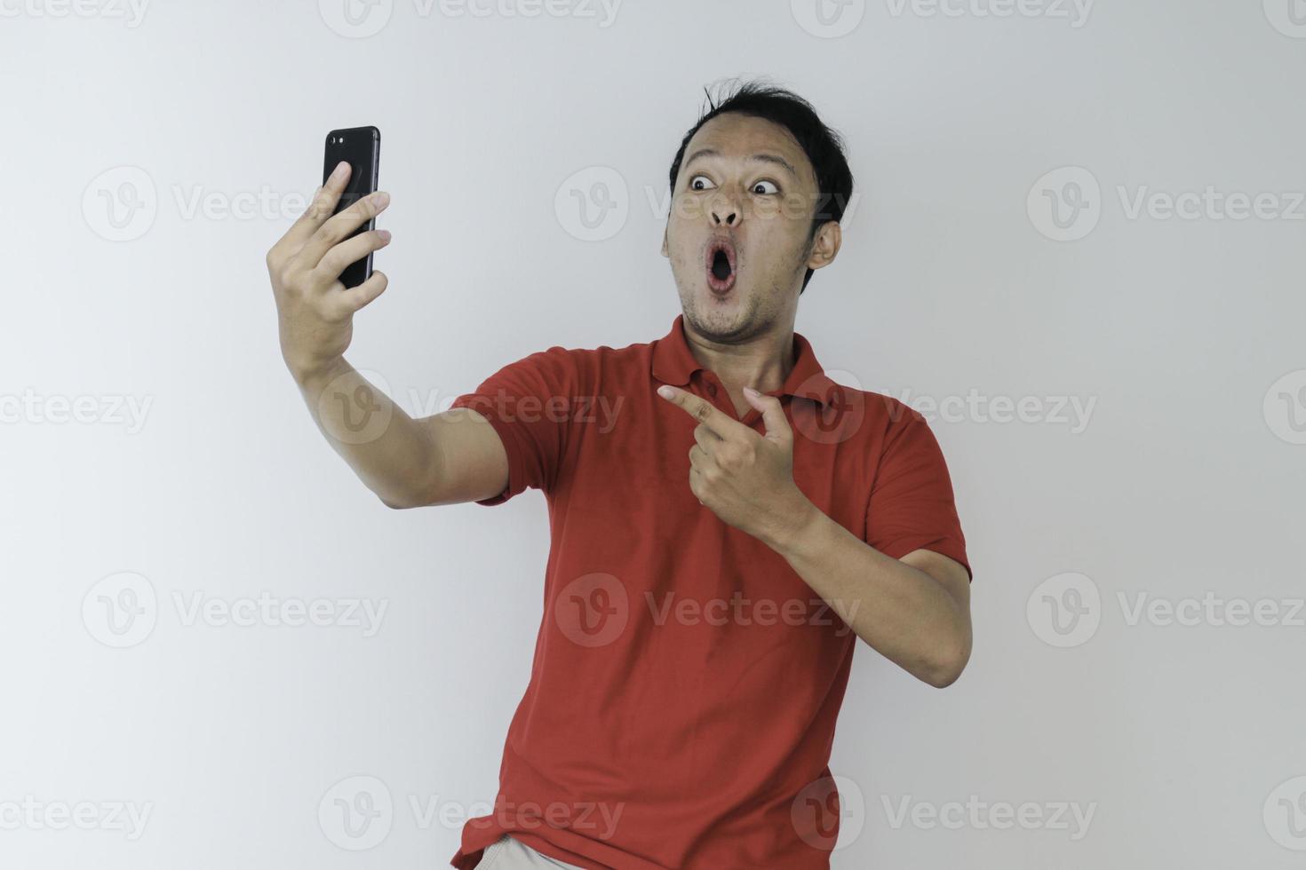 Wow face of Young Asian man shocked what he see in the smartphone on isolated grey background. photo