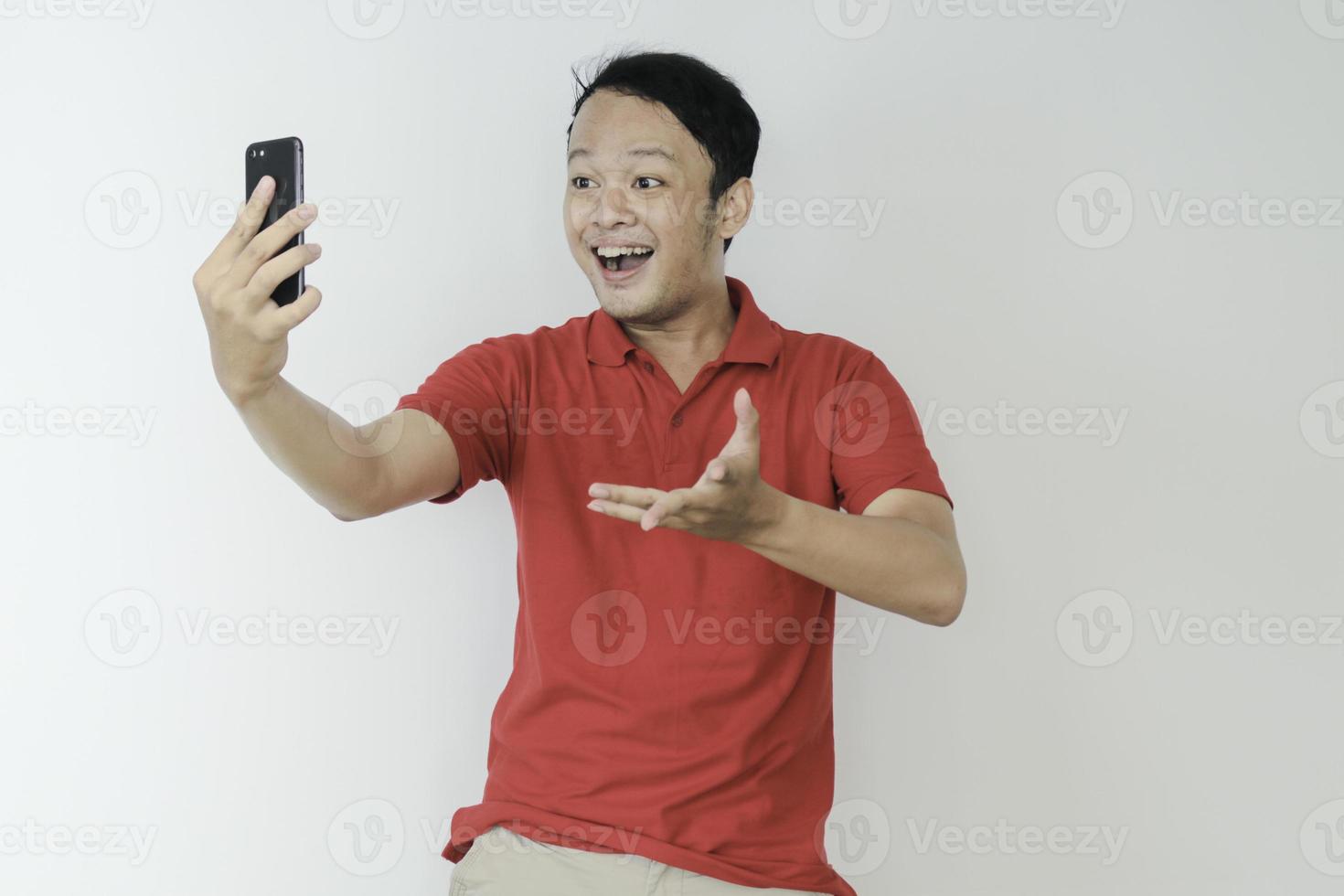 Young Asian man shocked and happy with what he see in the smartphone on isolated grey background. photo