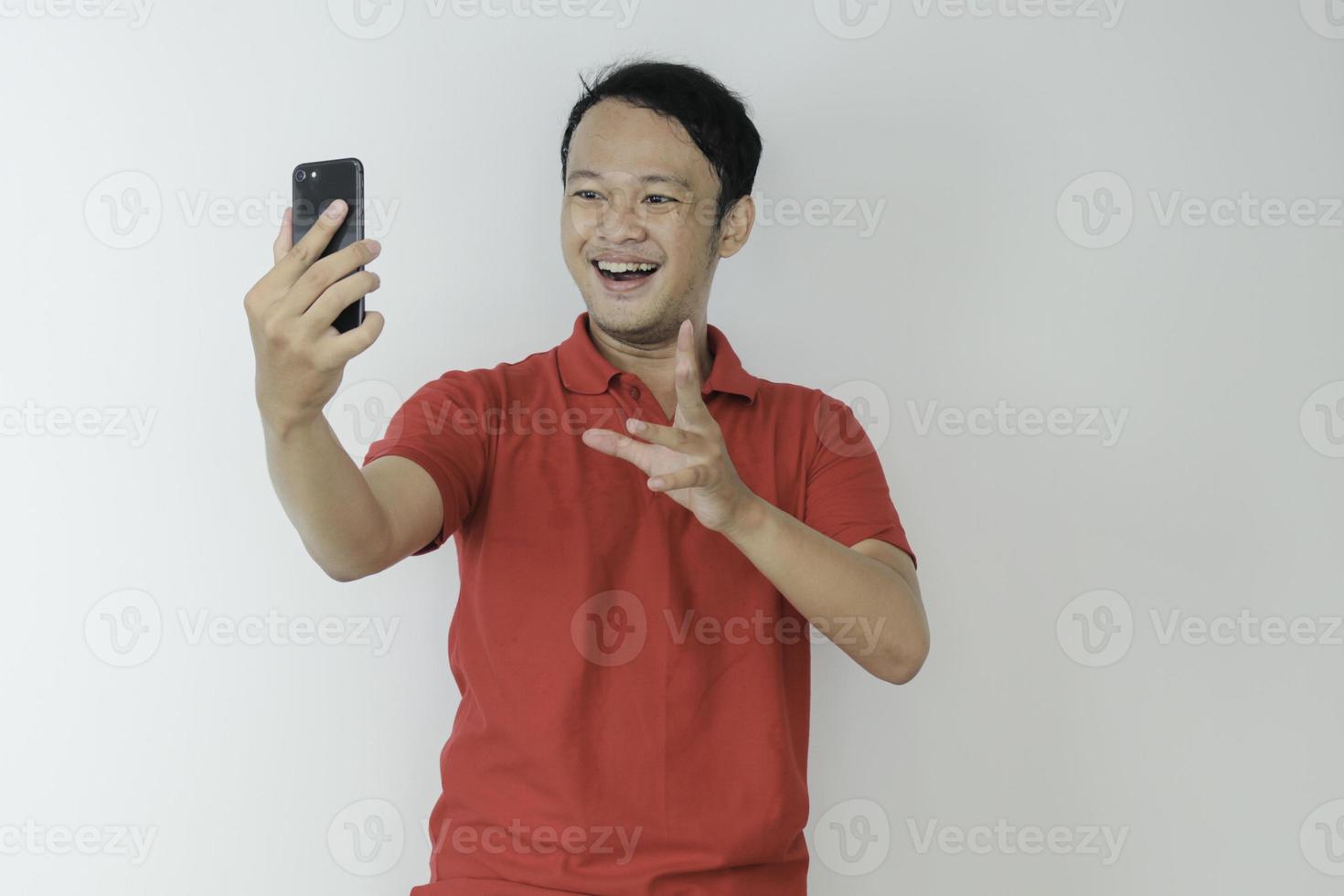 Young Asian man shocked and happy with what he see in the smartphone on isolated grey background. photo