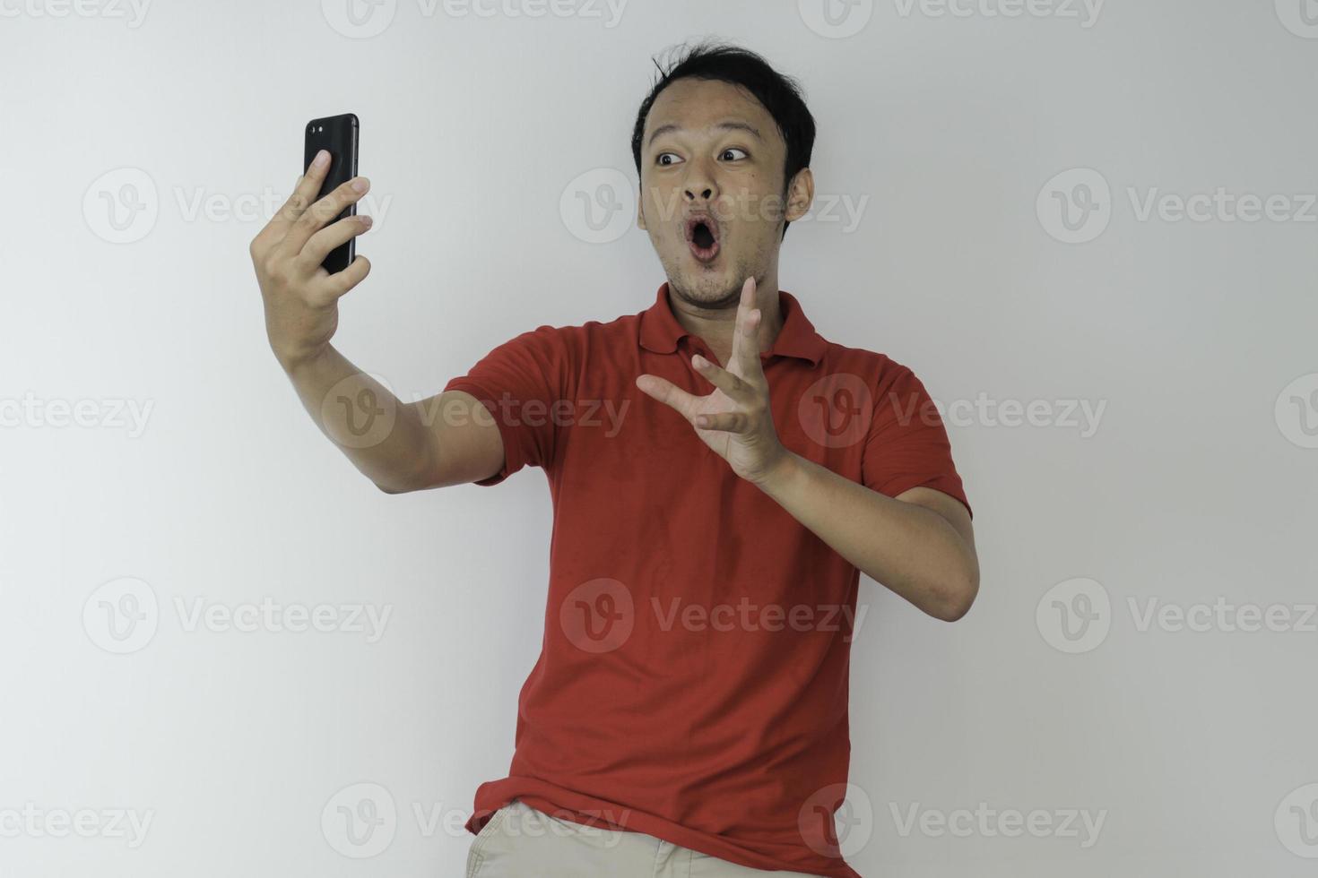 Wow face of Young Asian man shocked what he see in the smartphone on isolated grey background. photo