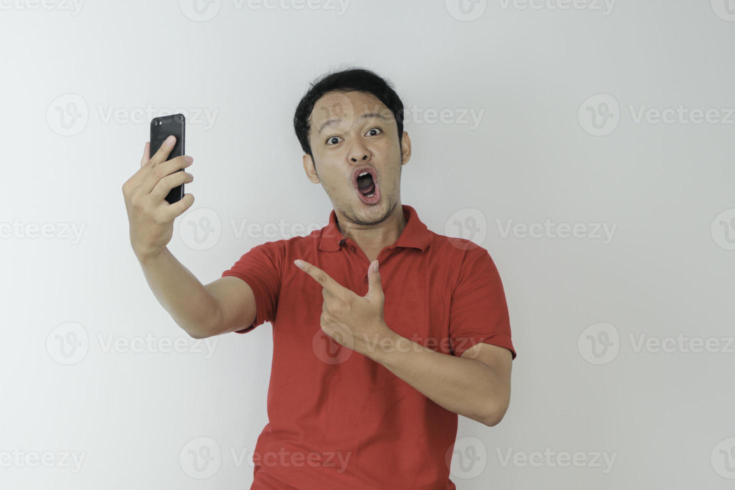 wow, la cara de un joven asiático se sorprendió por lo que vio en el teléfono inteligente con un fondo gris aislado. foto