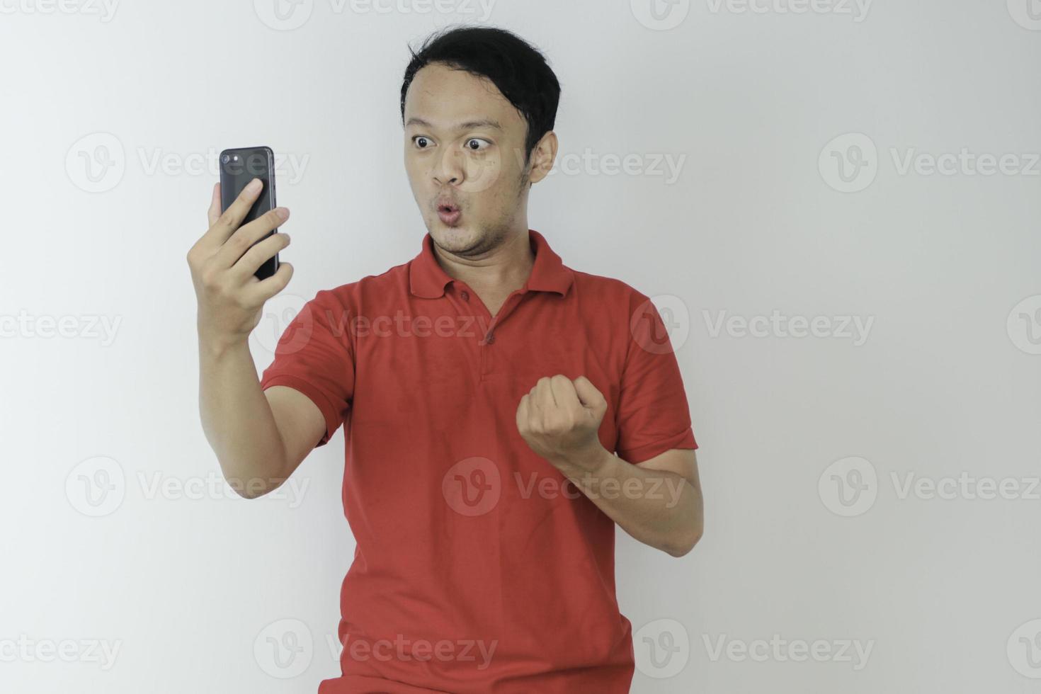 Wow face of Young Asian man shocked what he see in the smartphone on isolated grey background. photo