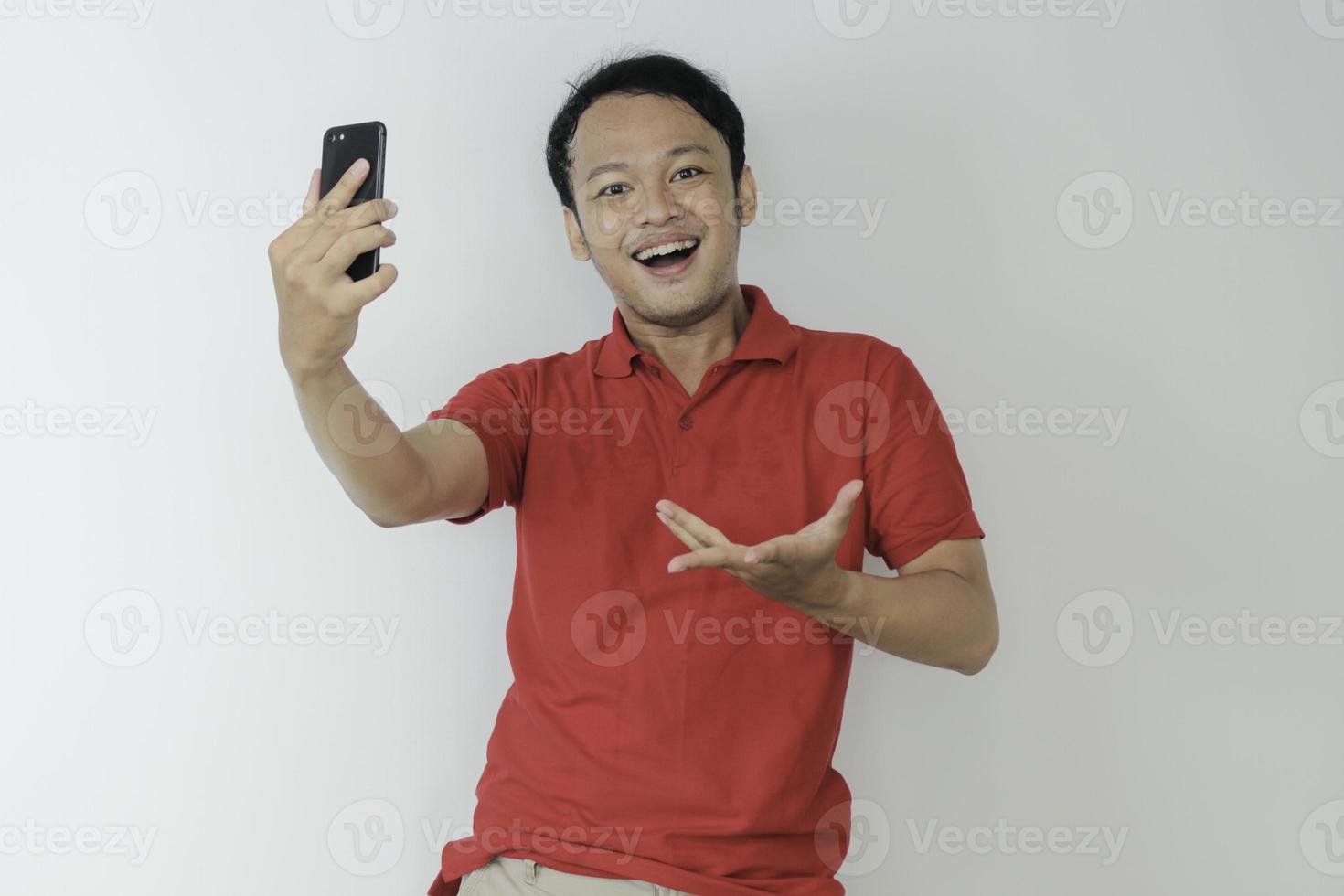 Young Asian man shocked and happy with what he see in the smartphone on isolated grey background. photo