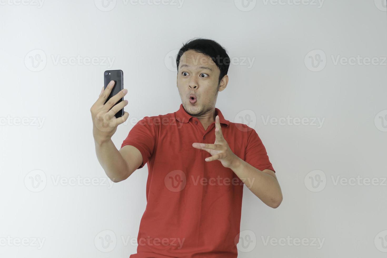 Wow face of Young Asian man shocked what he see in the smartphone on isolated grey background. photo
