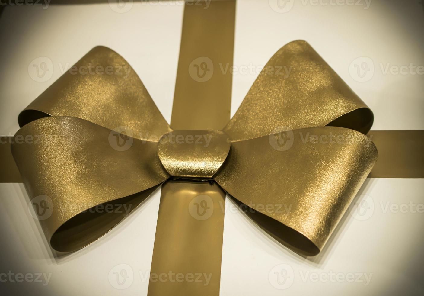 A close up of a big golden bow on a white present photo