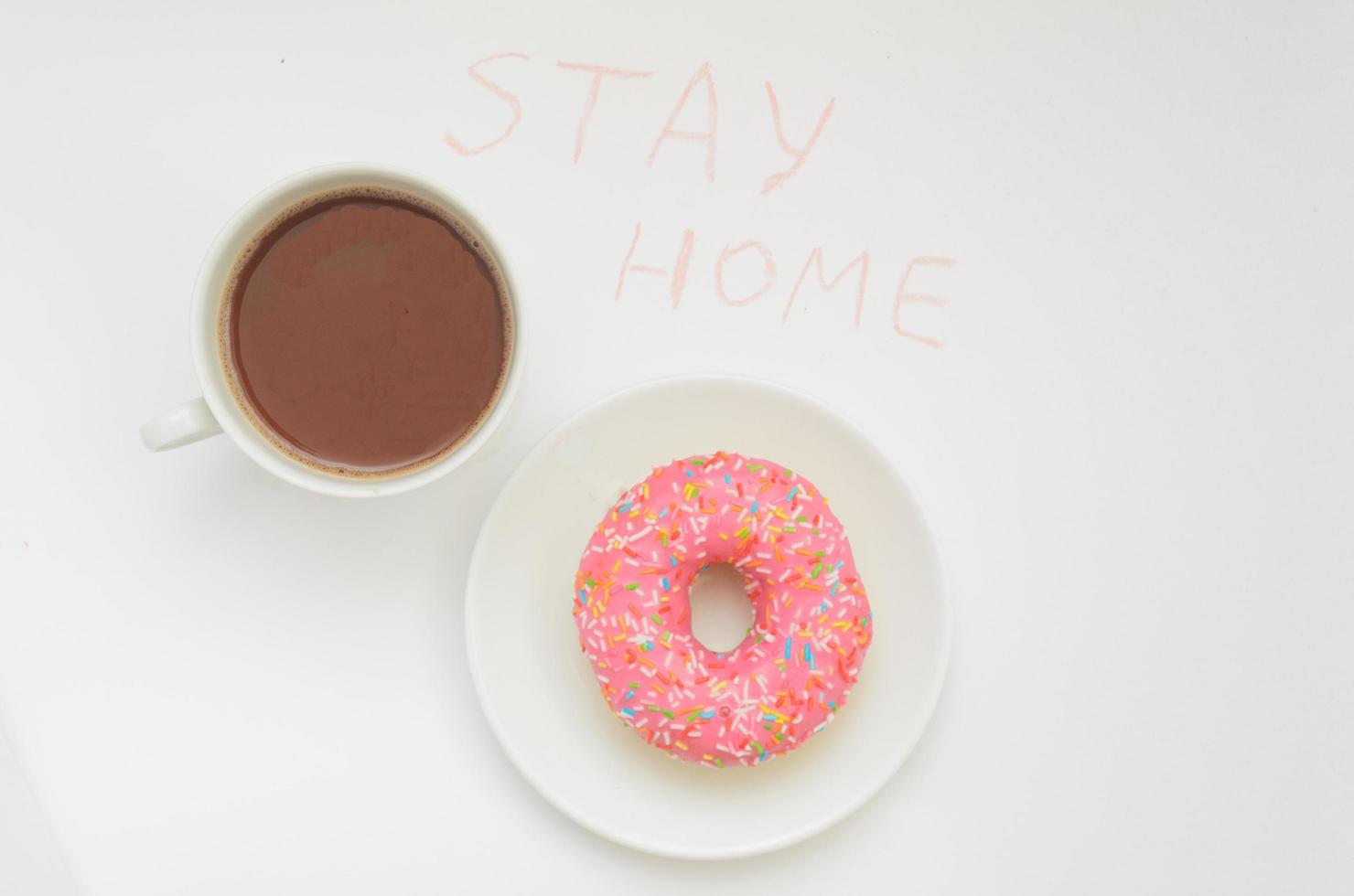 Top view,A cup of cacao drink and one glazed pink donut on white background.Sweet dessert.Stay home in warm photo