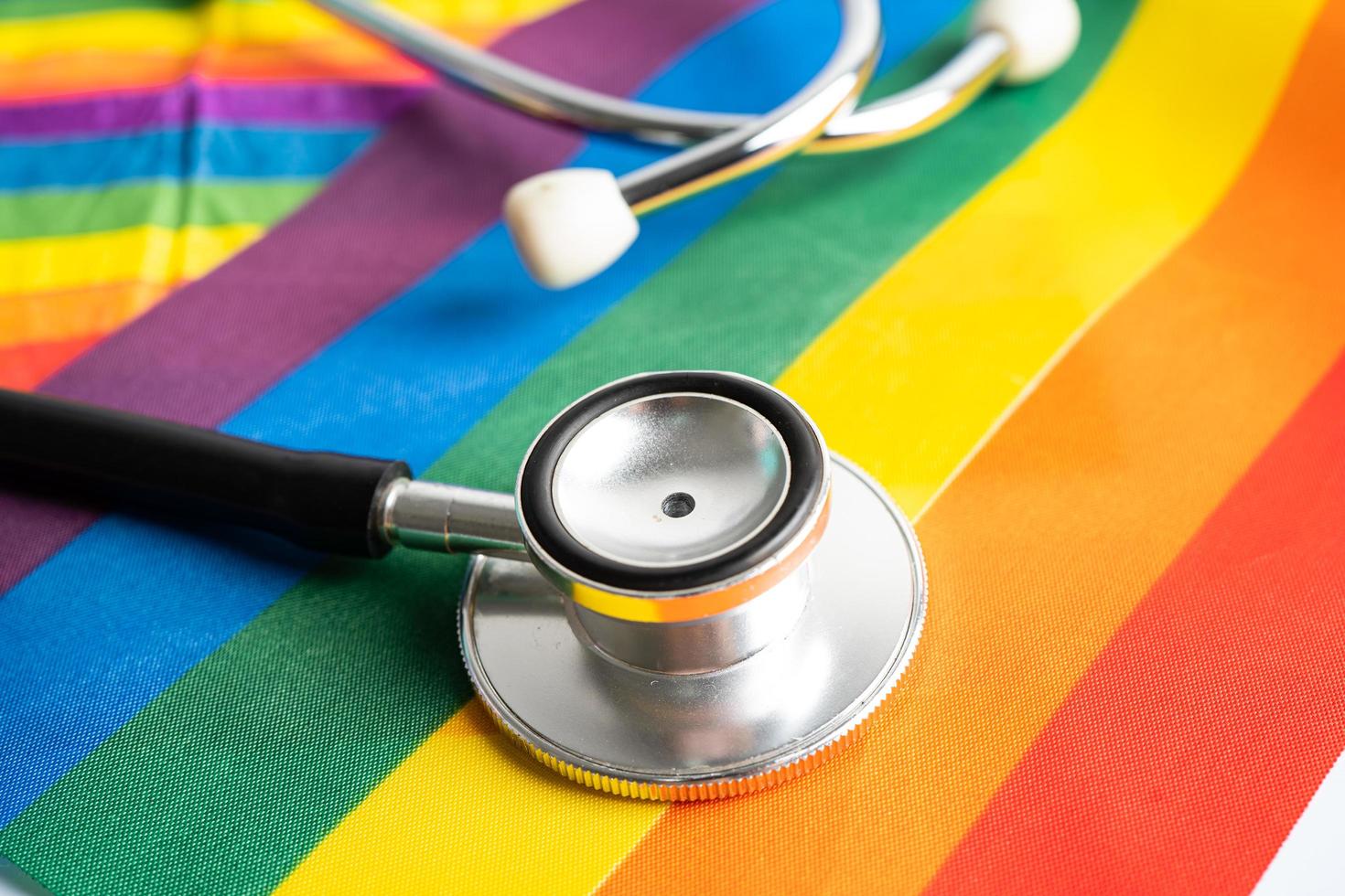 Black stethoscope on rainbow flag background, symbol of LGBT pride month  celebrate annual in June social, symbol of gay, lesbian, bisexual, transgender, human rights and peace. photo