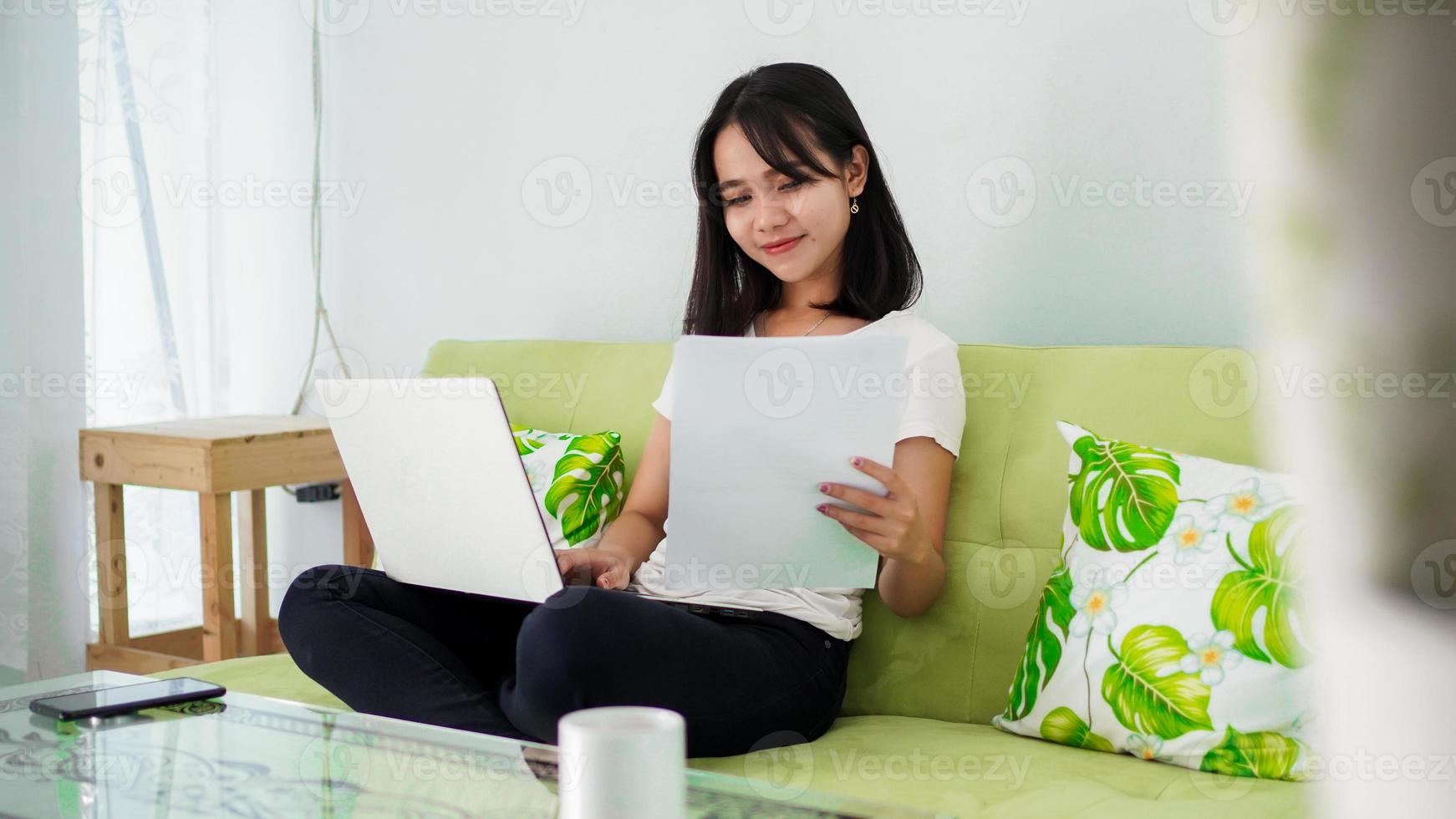 Young beautiful Asian woman working from home using laptop photo