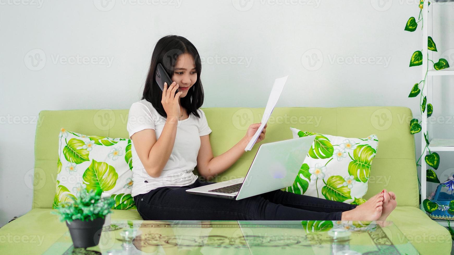 hermosas mujeres asiáticas que trabajan desde casa usando una computadora portátil y llamando por teléfono foto